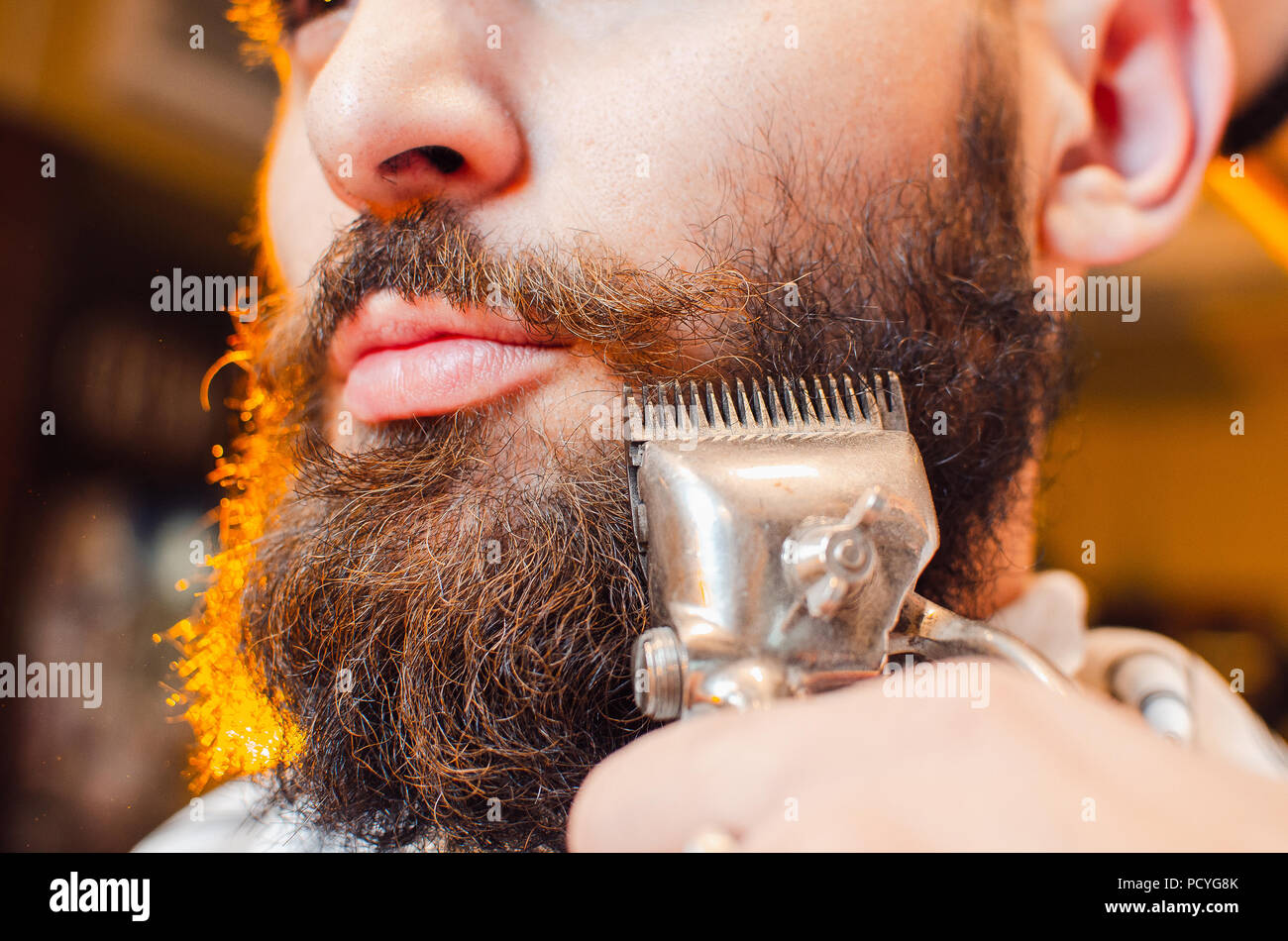Friseur schneidet einen Bart von Vintage Haarschneidemaschinen, ein junger hübscher Kerl mit Bart und Schnurrbart. Herren Friseursalon. Stockfoto