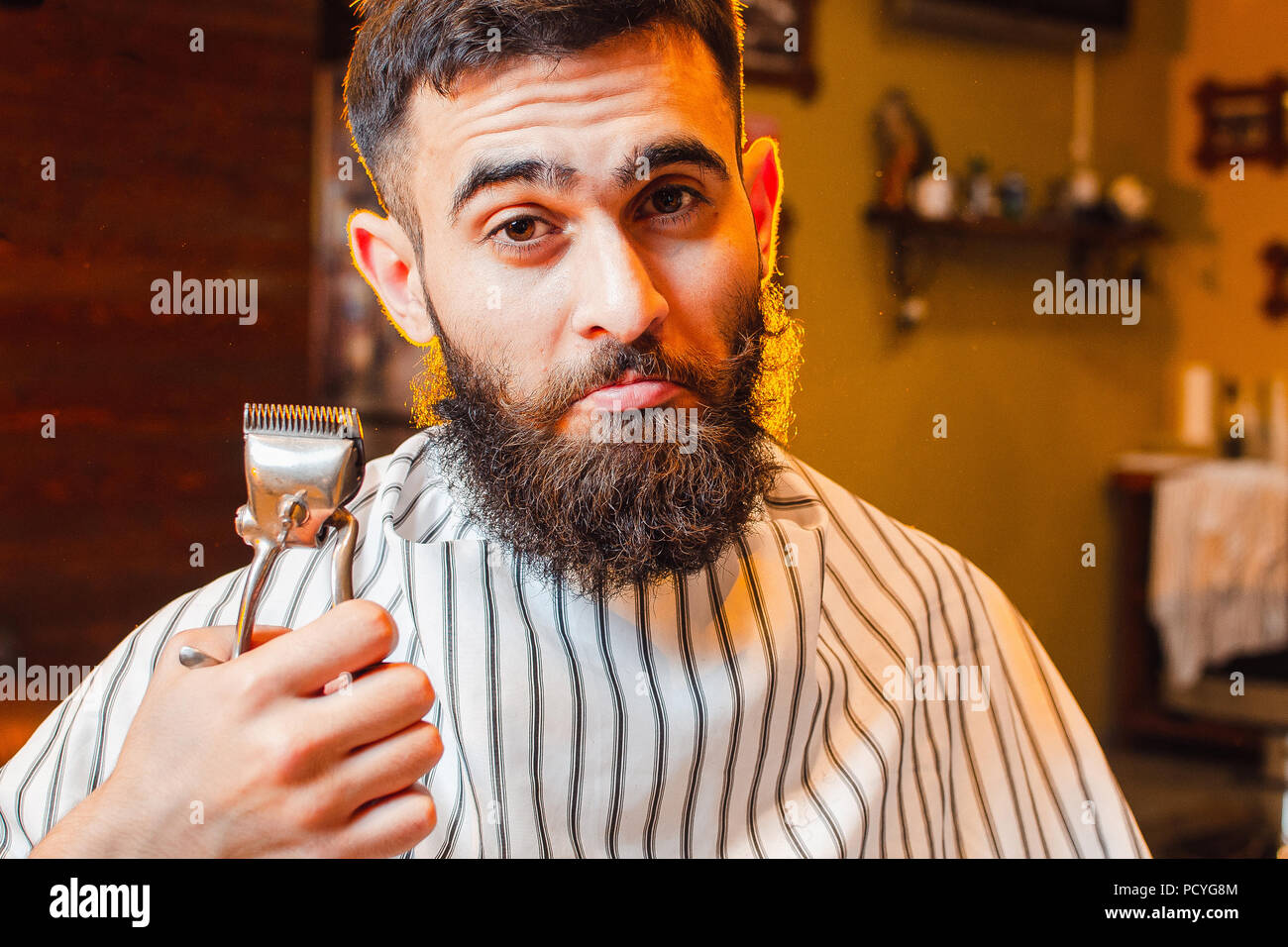 Ein junger hübscher Kerl mit Bart und Schnurrbart Holding vintage Hair Clips in seiner rechten Hand. Herren Friseursalon. Stockfoto