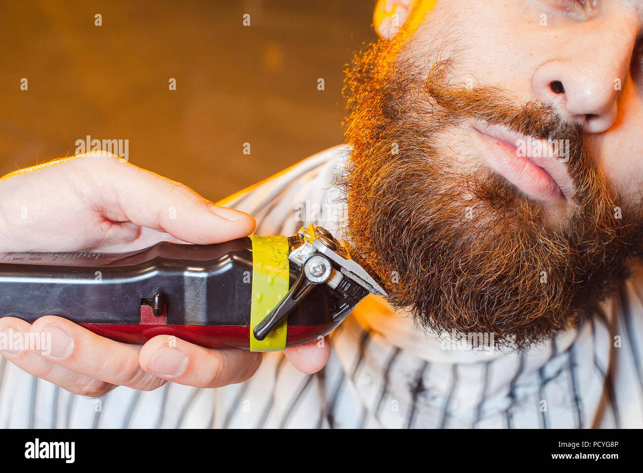 Friseur schneidet ein Bart mit einem Langhaarschneider auf ein junger  hübscher Kerl mit einem Schnurrbart. Haarschnitt von einem Bart in einer  männlichen Friseur Stockfotografie - Alamy