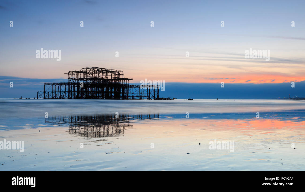 Die Ruinen der West Pier in Brighton bei Sonnenuntergang und einem niedrigen Spring Tide Stockfoto