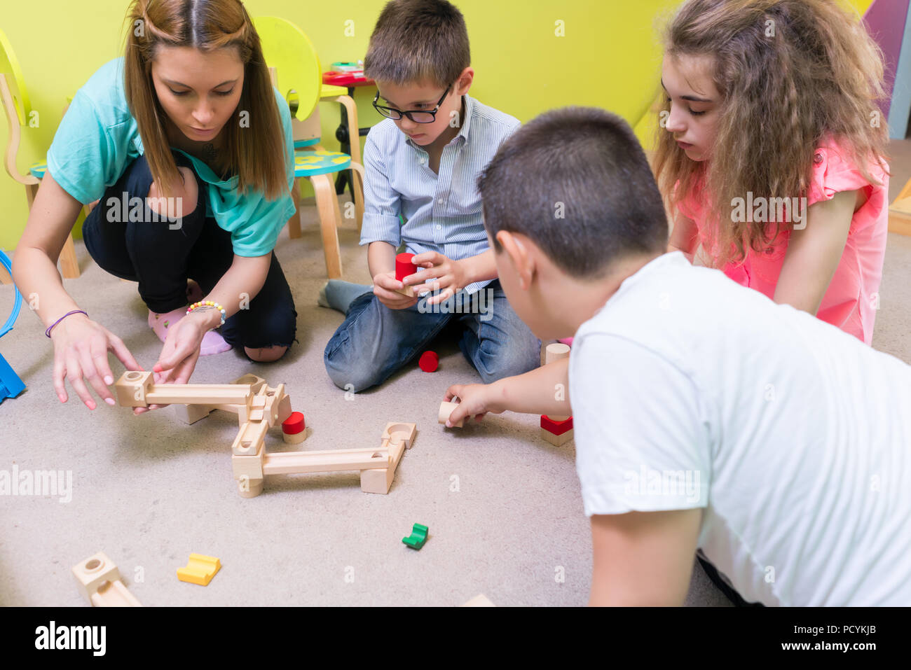 Engagierte Kindergärtnerin Kinder helfen mit Aufbau Stockfoto