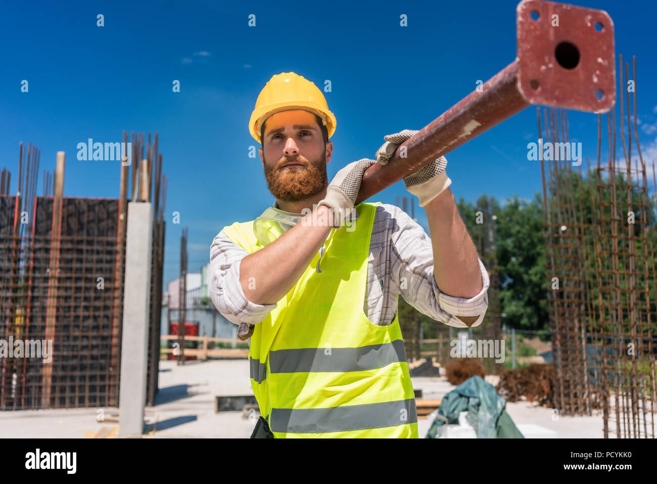 Blue-collar worker eine schwere metallische Bar während der Arbeit Stockfoto