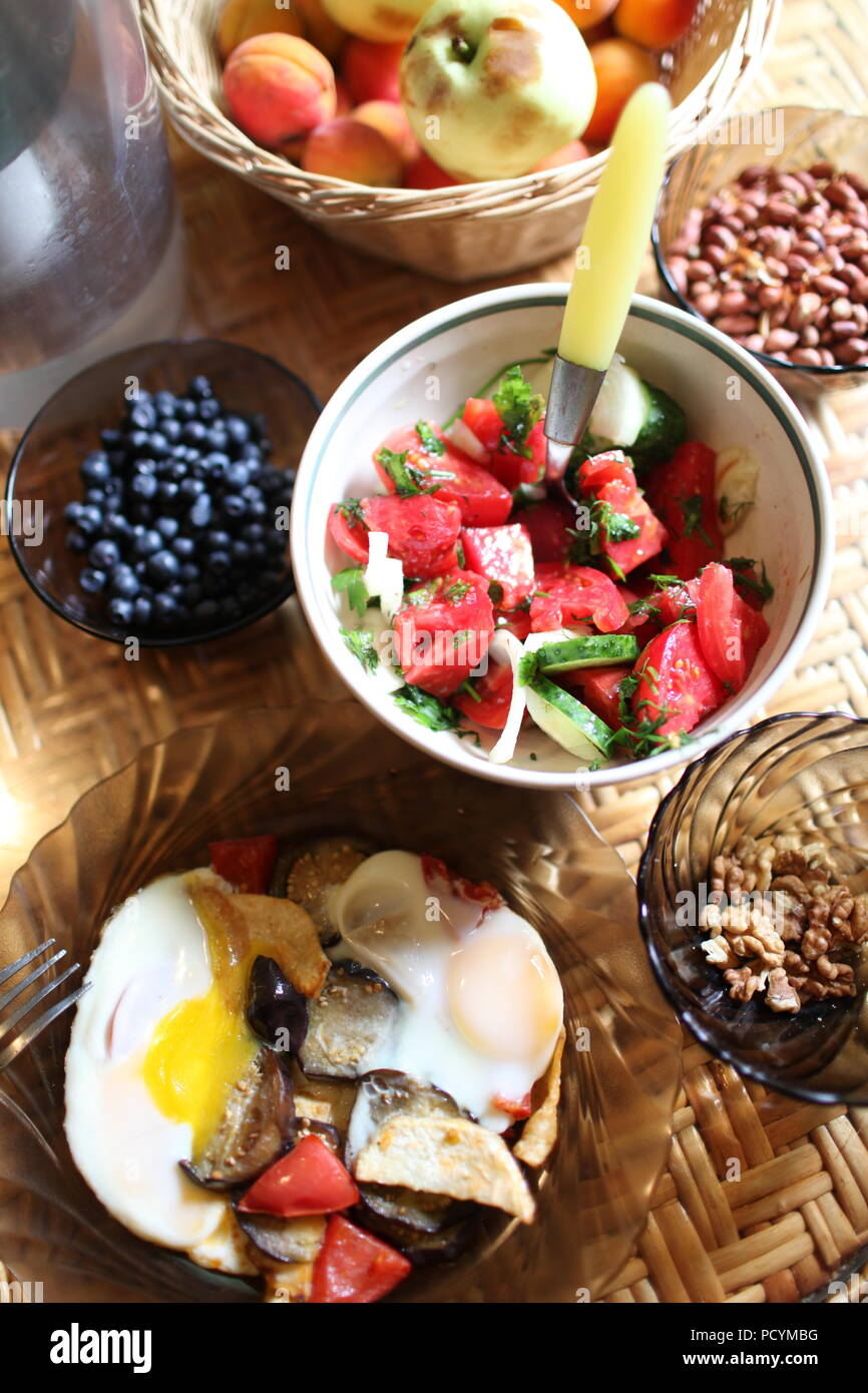 Ein Blick auf die Tabelle mit einer einfachen und Proteinen und Vitaminen reich gesund und reichlich Sommer Frühstück mit Gemüse, Beeren, Nüsse, Früchte und gebratene Eier Stockfoto