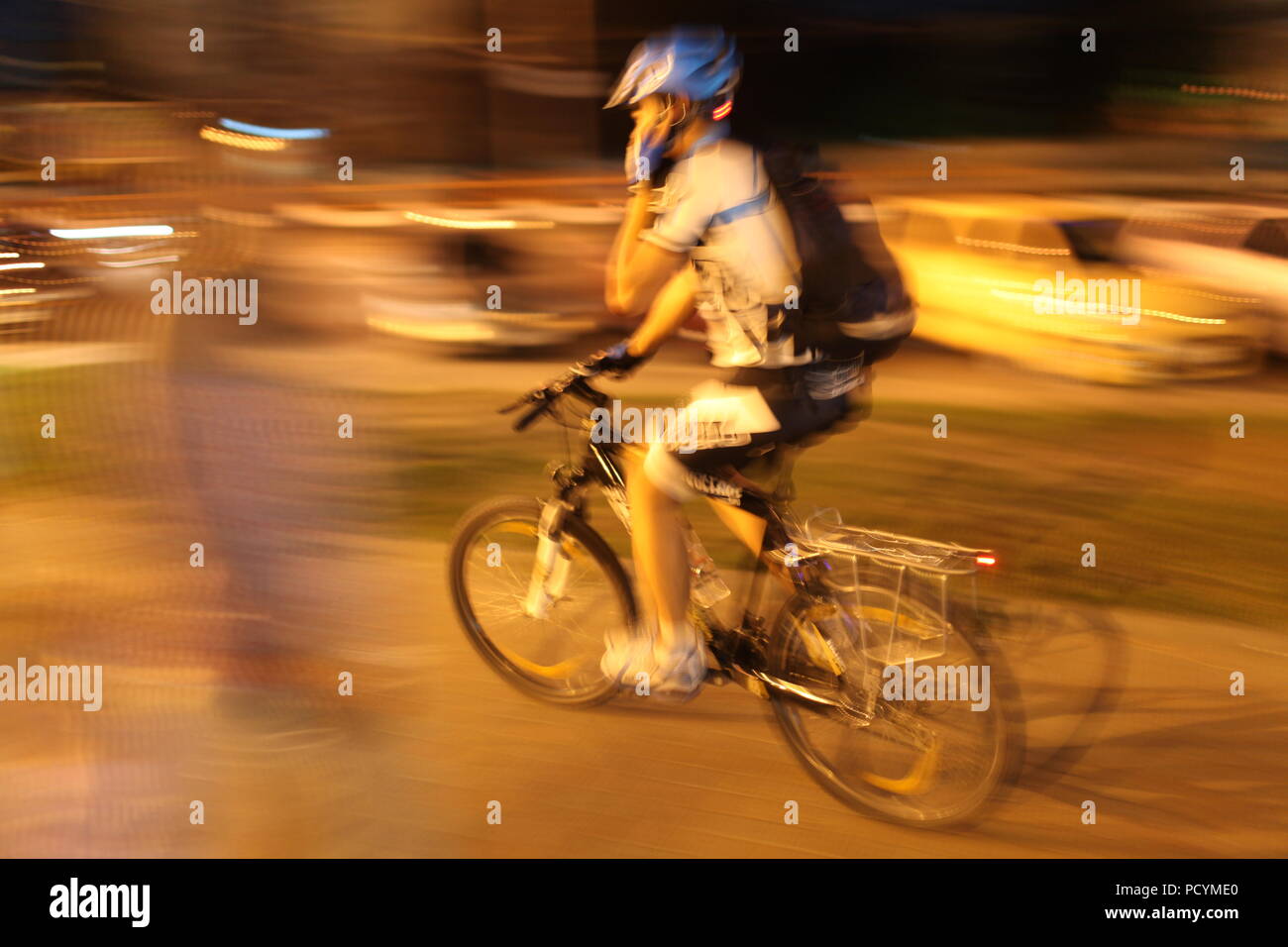 Radfahrer mit Sack, in Schutzhelm Pedale seiner Metall Pferd in Big City lights Gespräche auf seinem Weg Handy, holding Lenker mit einer Hand Stockfoto
