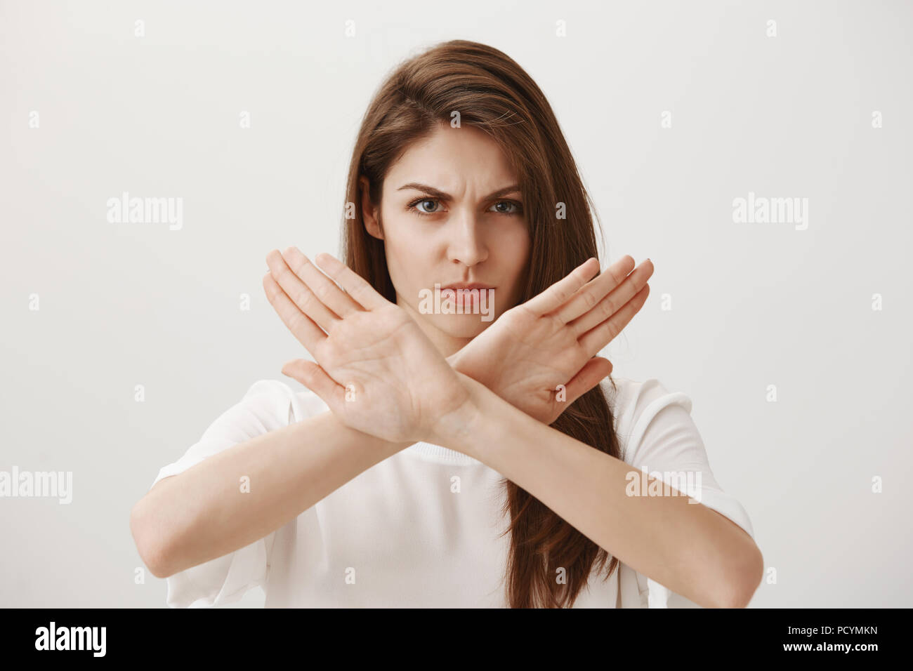 Stop, ich hasse solche Haltung. Portrait von wütend zornig in attraktive europäische Mädchen zeigen, keine oder Abneigung Geste mit verschränkten Armen, runzelte die Stirn und Stockfoto
