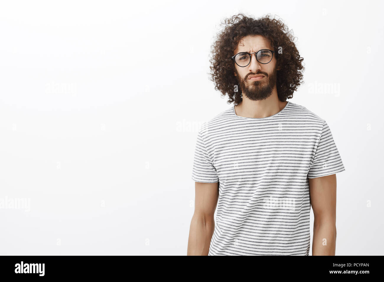 Verdächtig nachdenklich attraktive Hispanic Kerl in trendigen Gläser, Anheben der Augenbrauen in Zweifel und starrte Strenge und konzentrierte sich auf Kamera, hören Sie vorsichtig Stockfoto