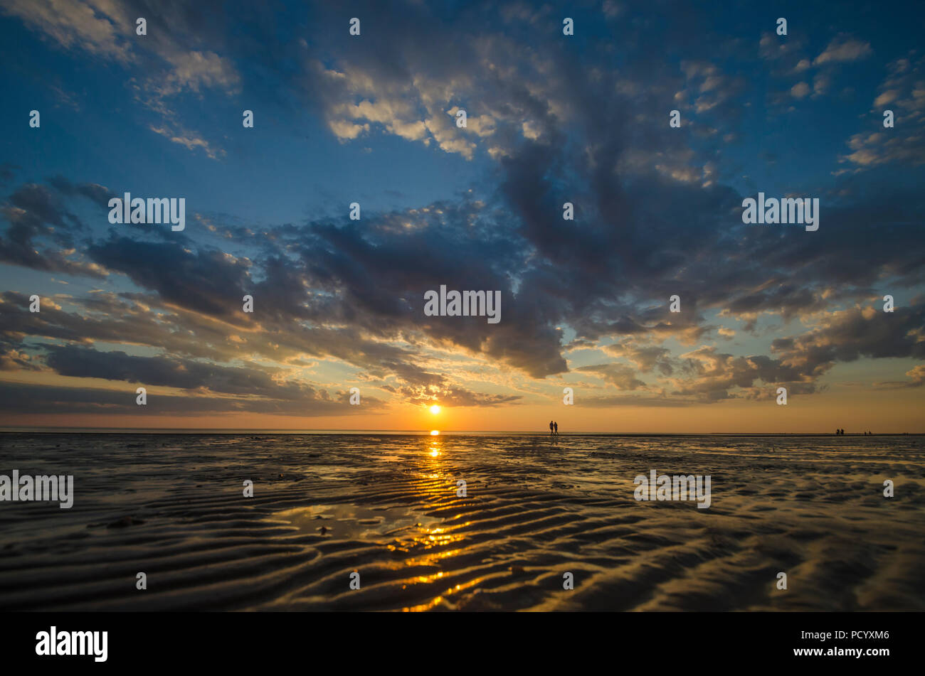 Zwei Menschen zu Fuß am Strand entlang in den Sonnenuntergang Stockfoto