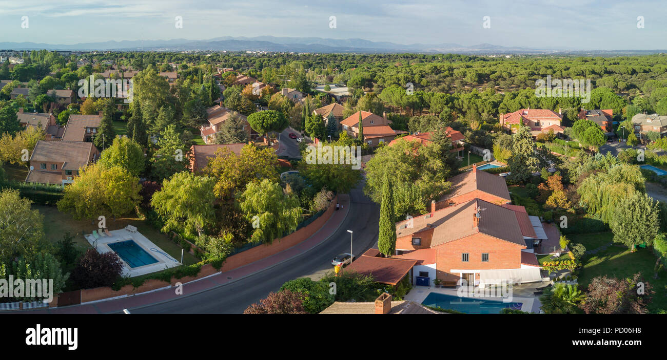 Ein Luftbild von der Drohne einer Nachbarschaft in einem Wald am Stadtrand von Madrid Stadt, die auf den weiten Horizont mit seinen Skyline gesehen werden kann. Stockfoto