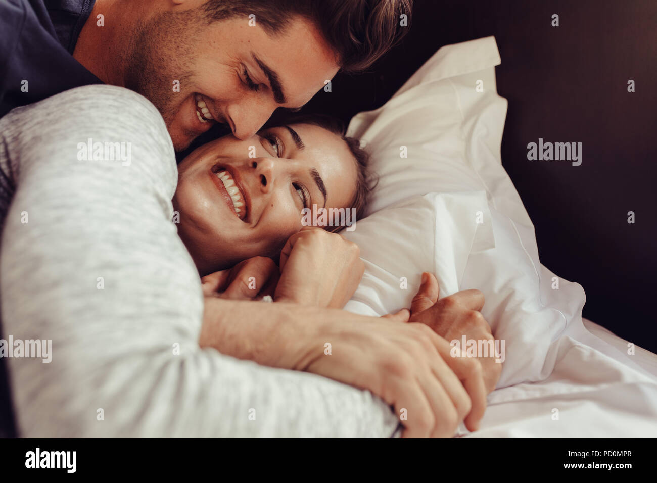 Lächelnden jungen Paare zusammen liegend auf dem Bett. Romantische junge Paar im Bett lag. Stockfoto
