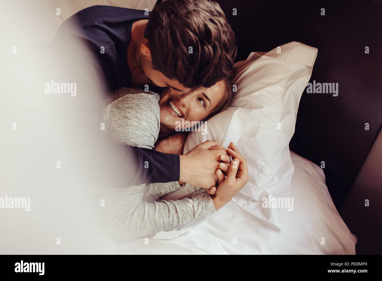 Romantische junge Paar in Liebe liegend auf dem Bett. Schönes Paar im Bett mit einem Lächeln. Stockfoto