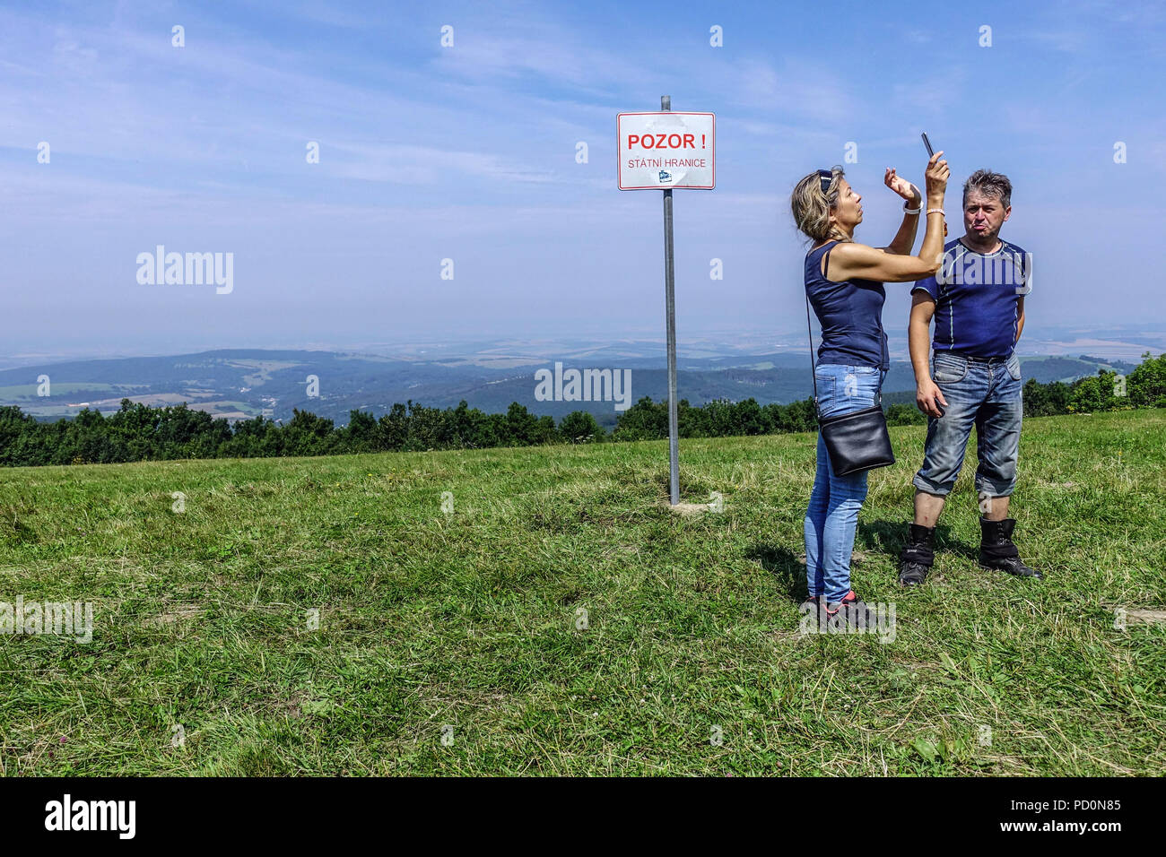 Der Mann und die Frau an der tschechischen Grenze zur Slowakei vor dem Schild "Vorsicht vor der Grenze "Weißen Karpaten, Veľká Javorina, Slowakei Stockfoto