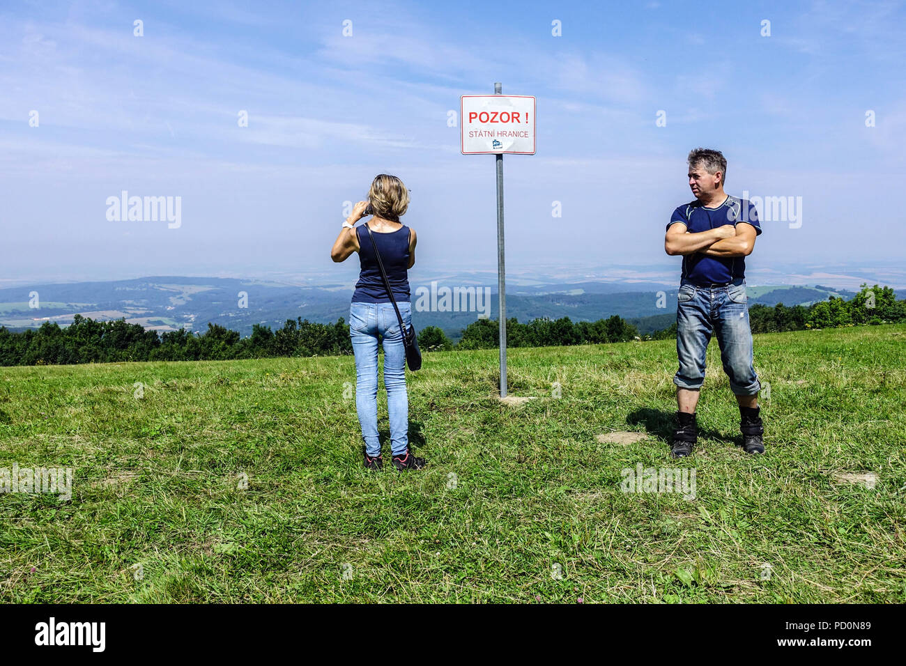 Der Mann und die Frau an der tschechischen Grenze zur Slowakei vor dem Schild "Vorsicht vor der Grenze "Weißen Karpaten, Veľká Javorina, Slowakei Stockfoto