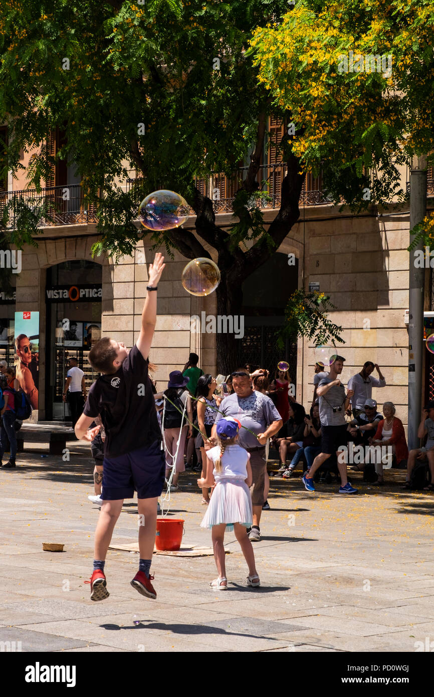 Kinder spielen mit Seifenblasen, die durch eine Straße Performer in der Plaza, Avinguda Catedral, 5, Barcelona, Spanien Stockfoto