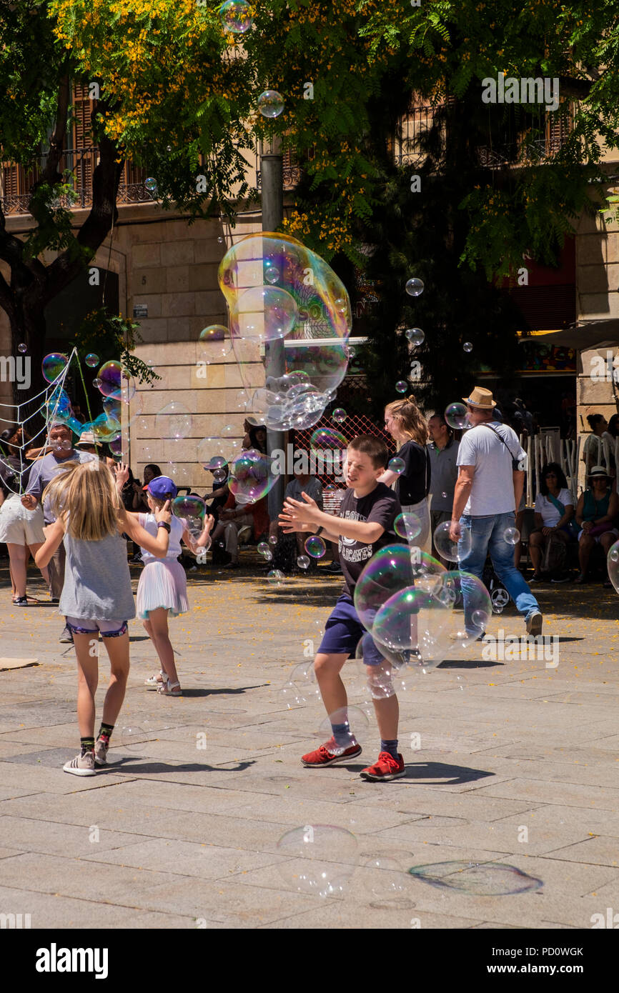 Kinder spielen mit Seifenblasen, die durch eine Straße Performer in der Plaza, Avinguda Catedral, 5, Barcelona, Spanien Stockfoto