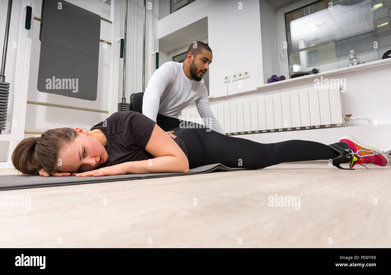 Low Angle View der männlichen Trainer massieren junge Frau in der Turnhalle. Stockfoto