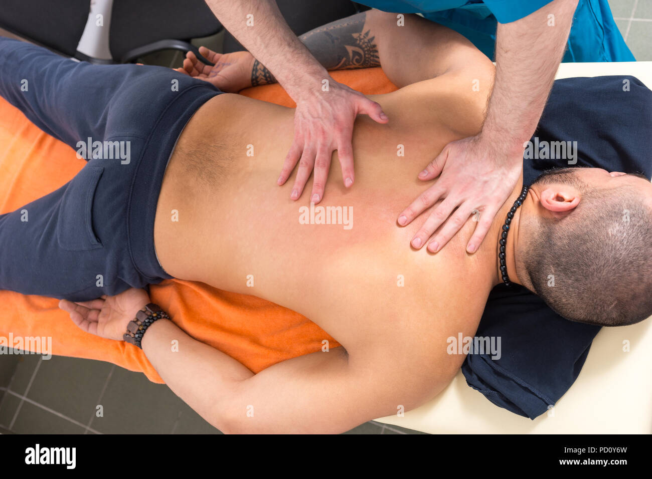 Hohe Betrachtungswinkel der männlichen Masseur Geben zurück Reiben Sie zu männlichen Klienten liegend auf Bauch auf der Massageliege Stockfoto