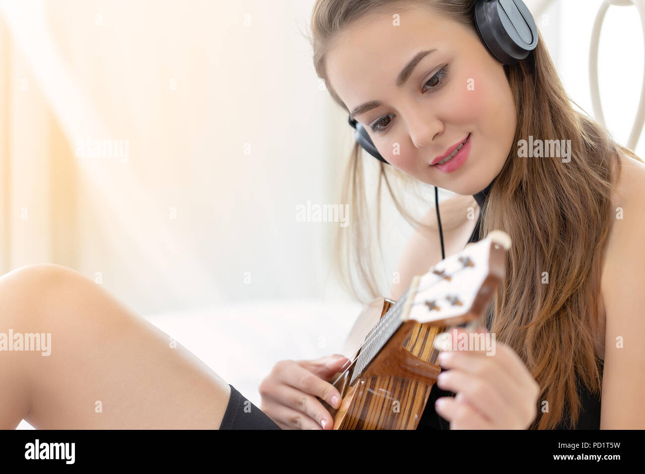Junge glücklich Mädchen spielen oder üben Sie Musik auf akustische Gitarre oder Ukulele. Stockfoto