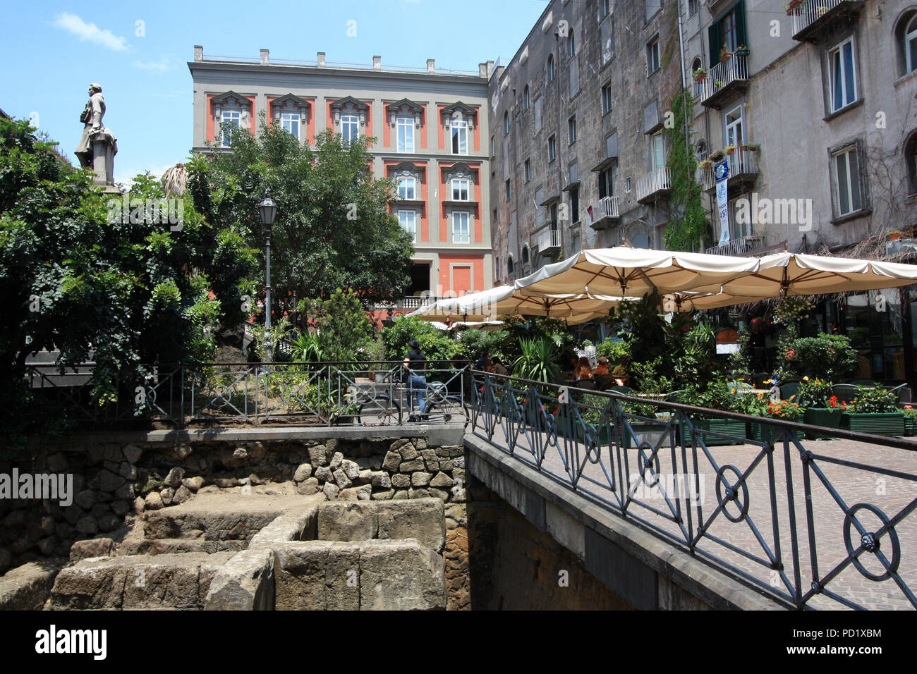 Die Menschen genießen das Leben unter Sonnenschirmen in einem Café an der Piazza Bellini in Catania, Italien, direkt neben Einige Ausgrabungen aus dem alten Römischen Reich Stockfoto