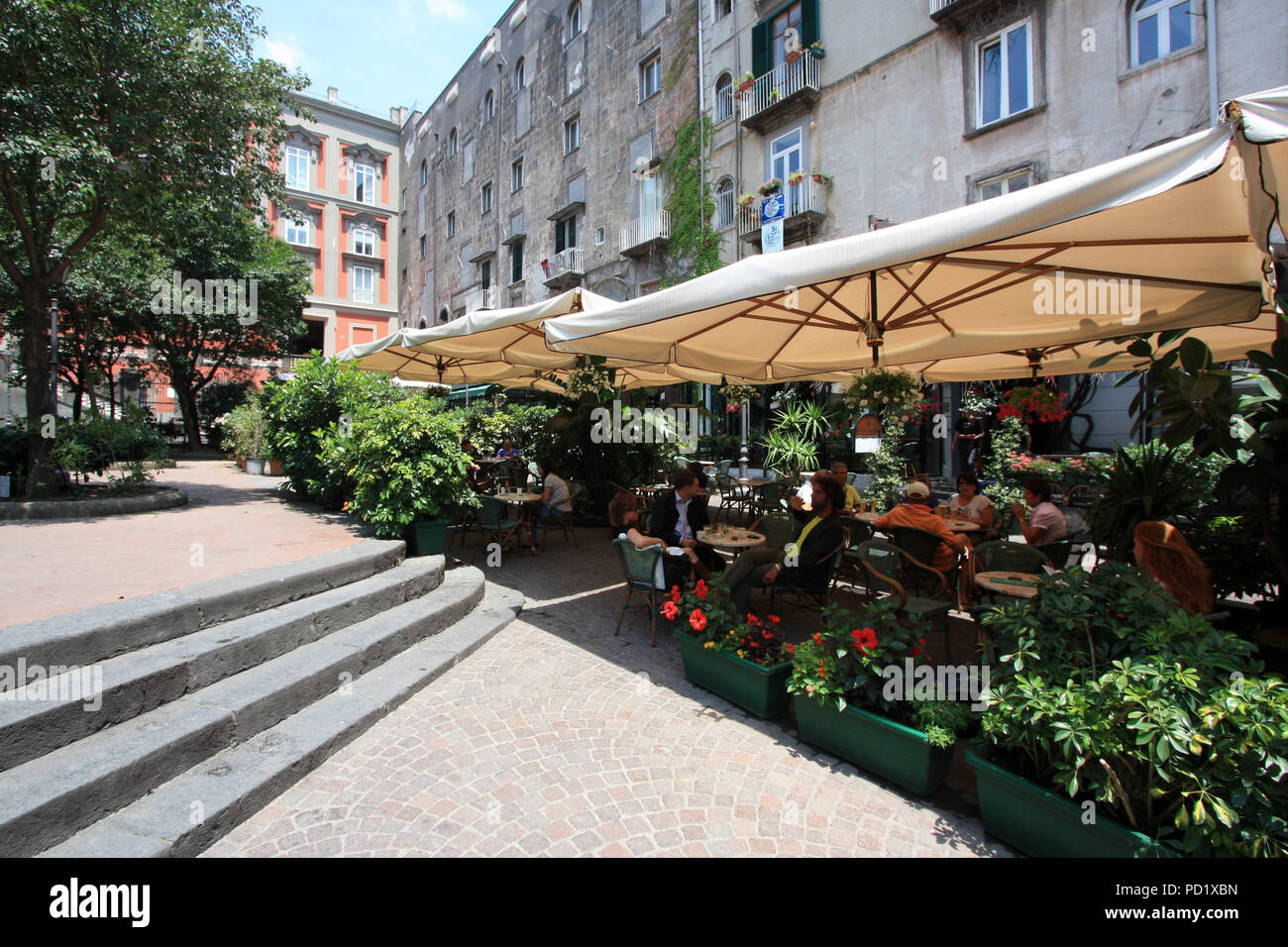 Die Menschen genießen das Leben unter Sonnenschirmen in einem Café an der Piazza Bellini in Catania, Italien, direkt neben Einige Ausgrabungen aus dem alten Römischen Reich Stockfoto