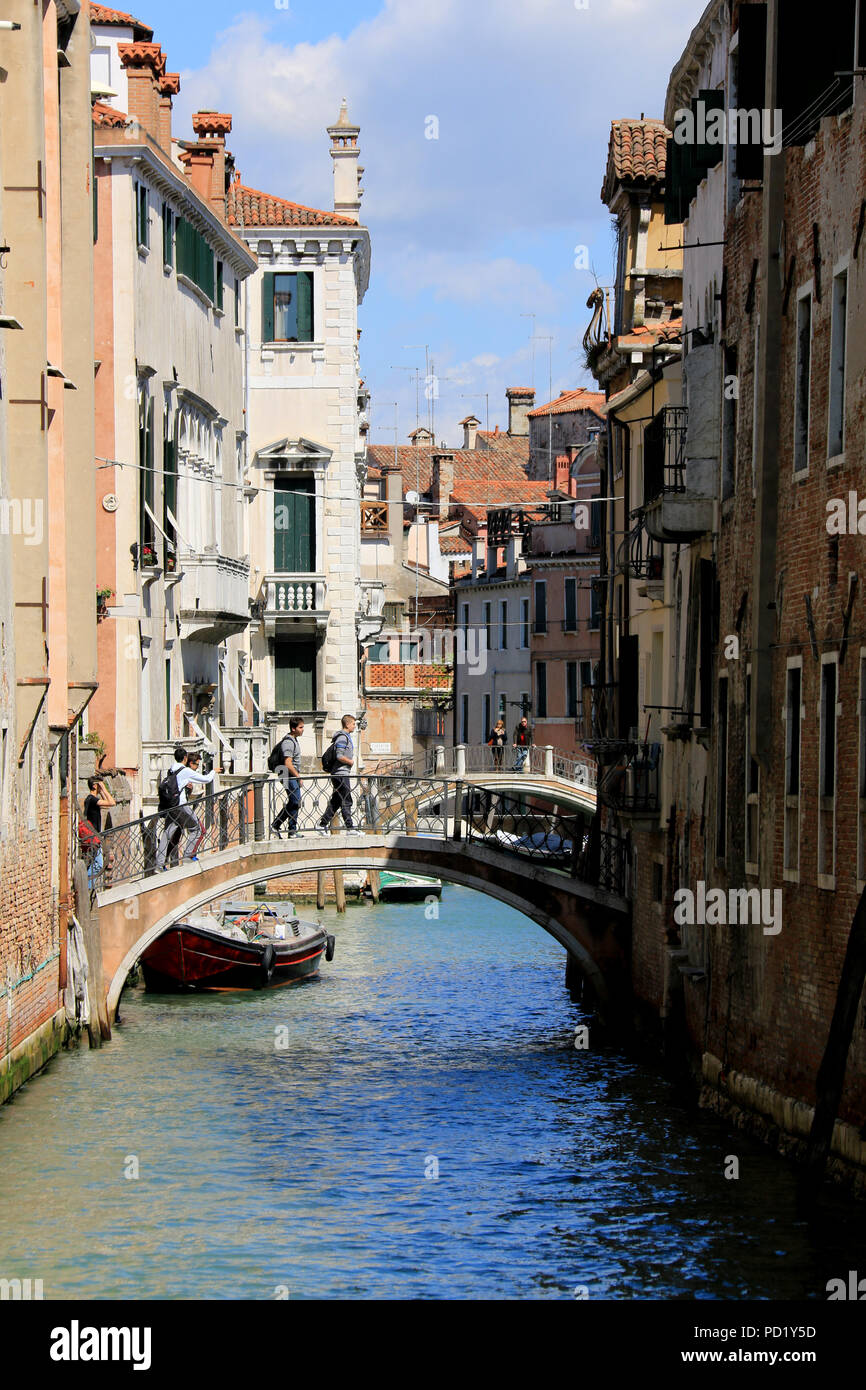 Touristen mit Rucksäcken über eine kleine Brücke in Venedig, Italien Stockfoto