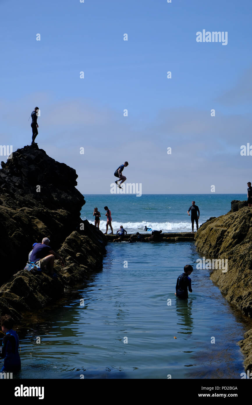 Bude, Cornwall, UK. Urlauber ins Meer springen von Felsen in einem natürlichen Pool, die Teilnahme an einem Sport bekannt als grabsteineffekt Stockfoto