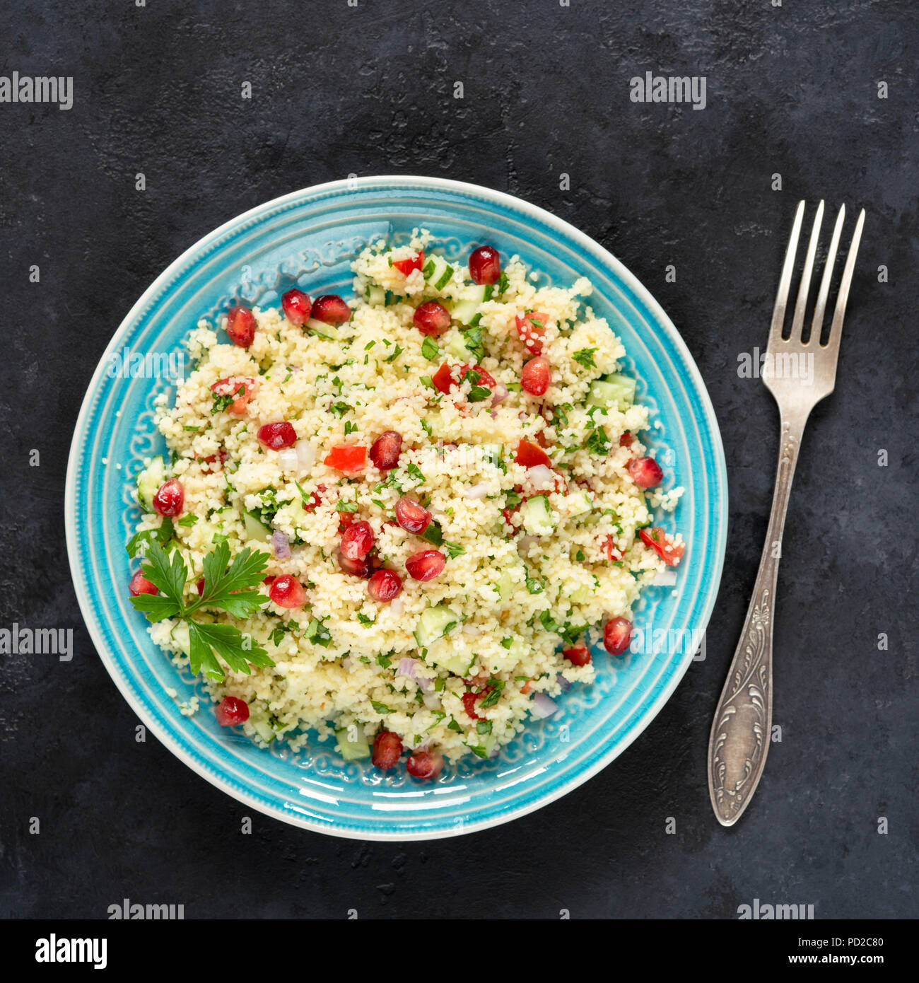 Tabbouleh Salat mit Couscous und Granatapfel Samen auf einem blauen Schild auf schwarzem Stein. Ansicht von oben, Quadrat Erntegut Stockfoto