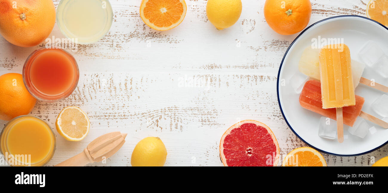Hausgemachte Orange und Zitrone Eis am Stiel und Zitrusfrüchte auf Stein schwarzen Hintergrund. Sommer essen Konzept. Stockfoto