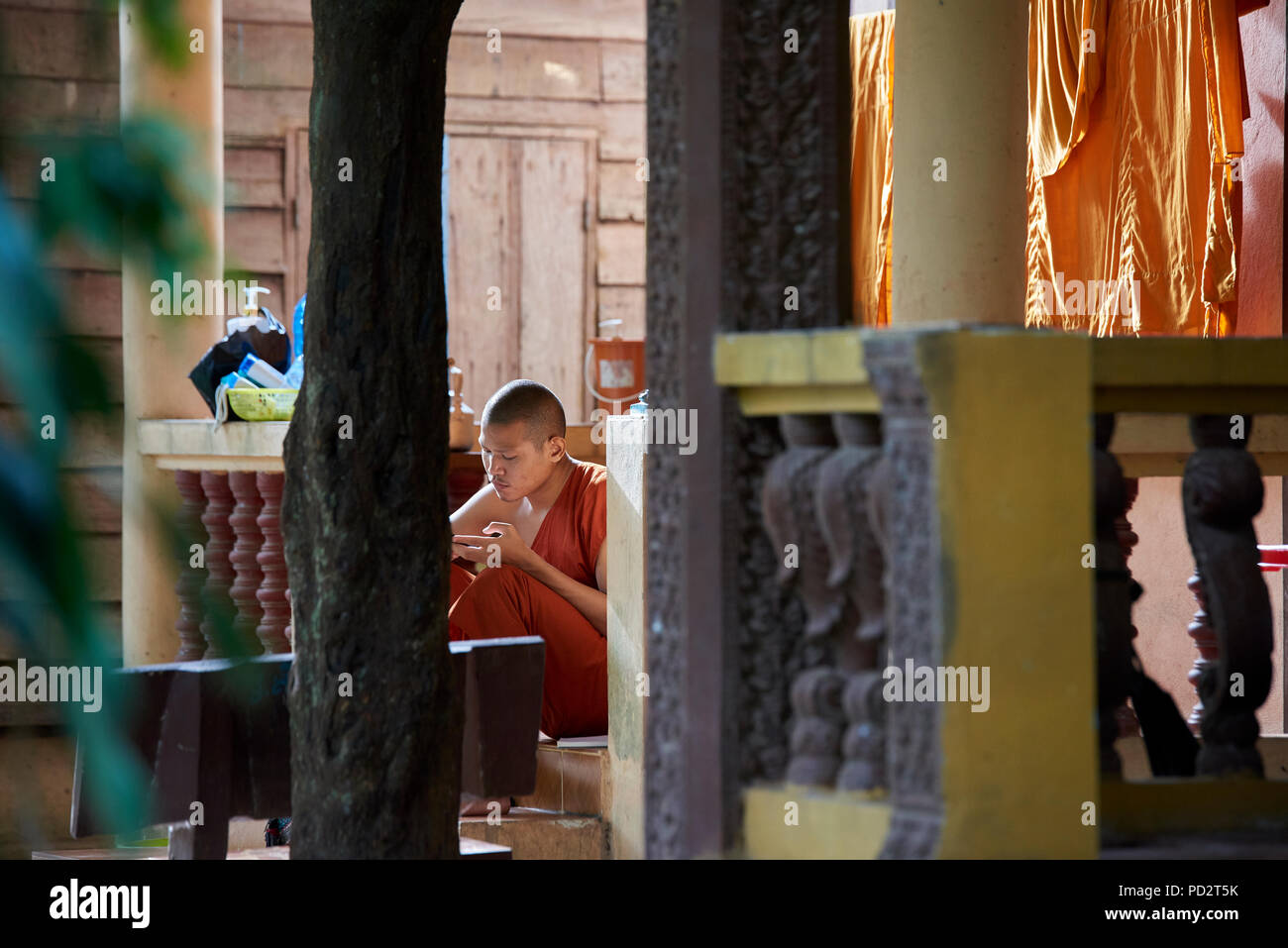 Ein junger buddhistischer Mönch entspannt in der Sonne in der Nähe seiner trocknen Bademäntel. In Siem Reap, Kambodscha. Stockfoto