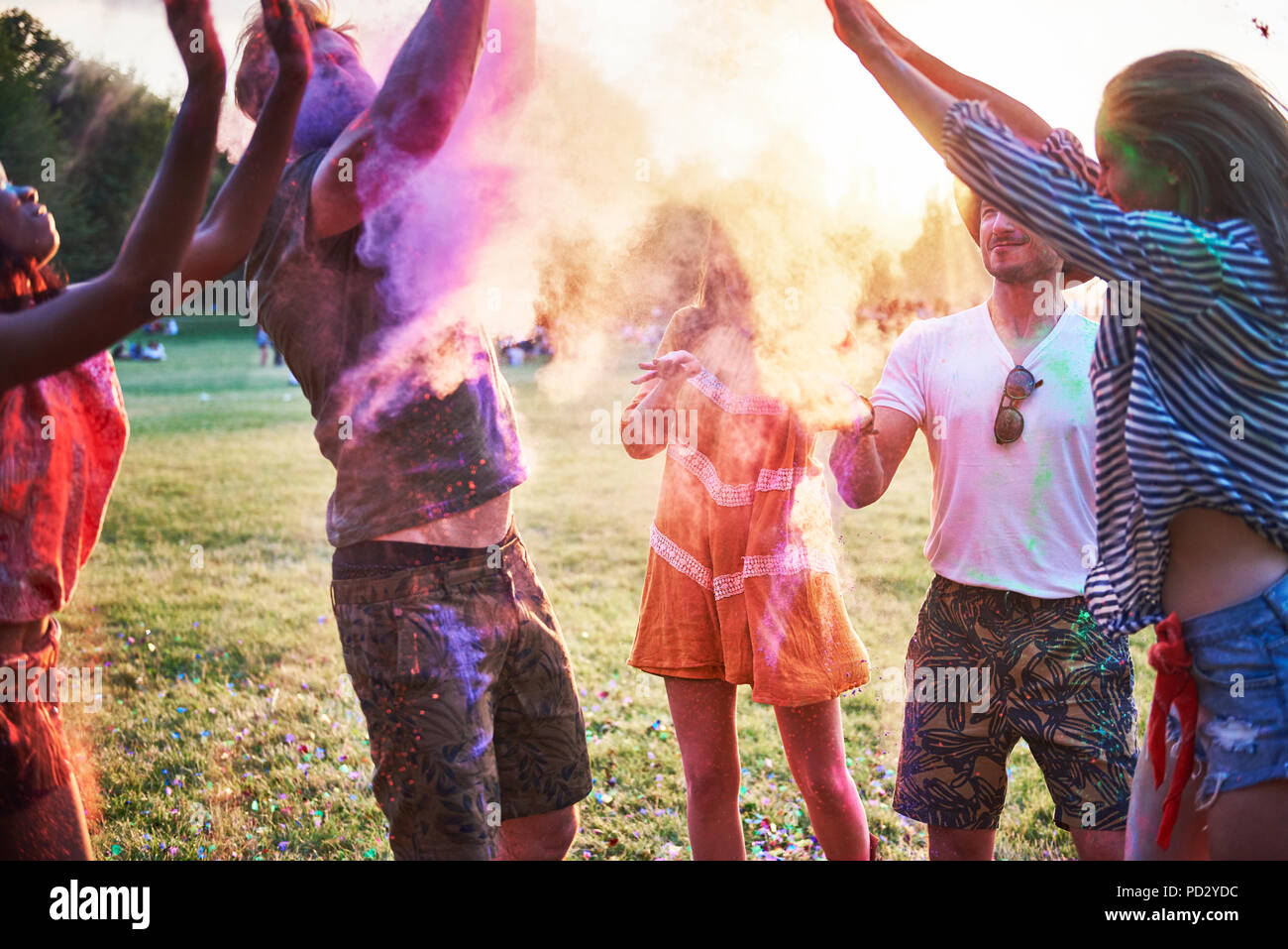 Fünf junge erwachsene Freunde tanzen und werfen farbige Kreide Pulver im Holi Festival Stockfoto