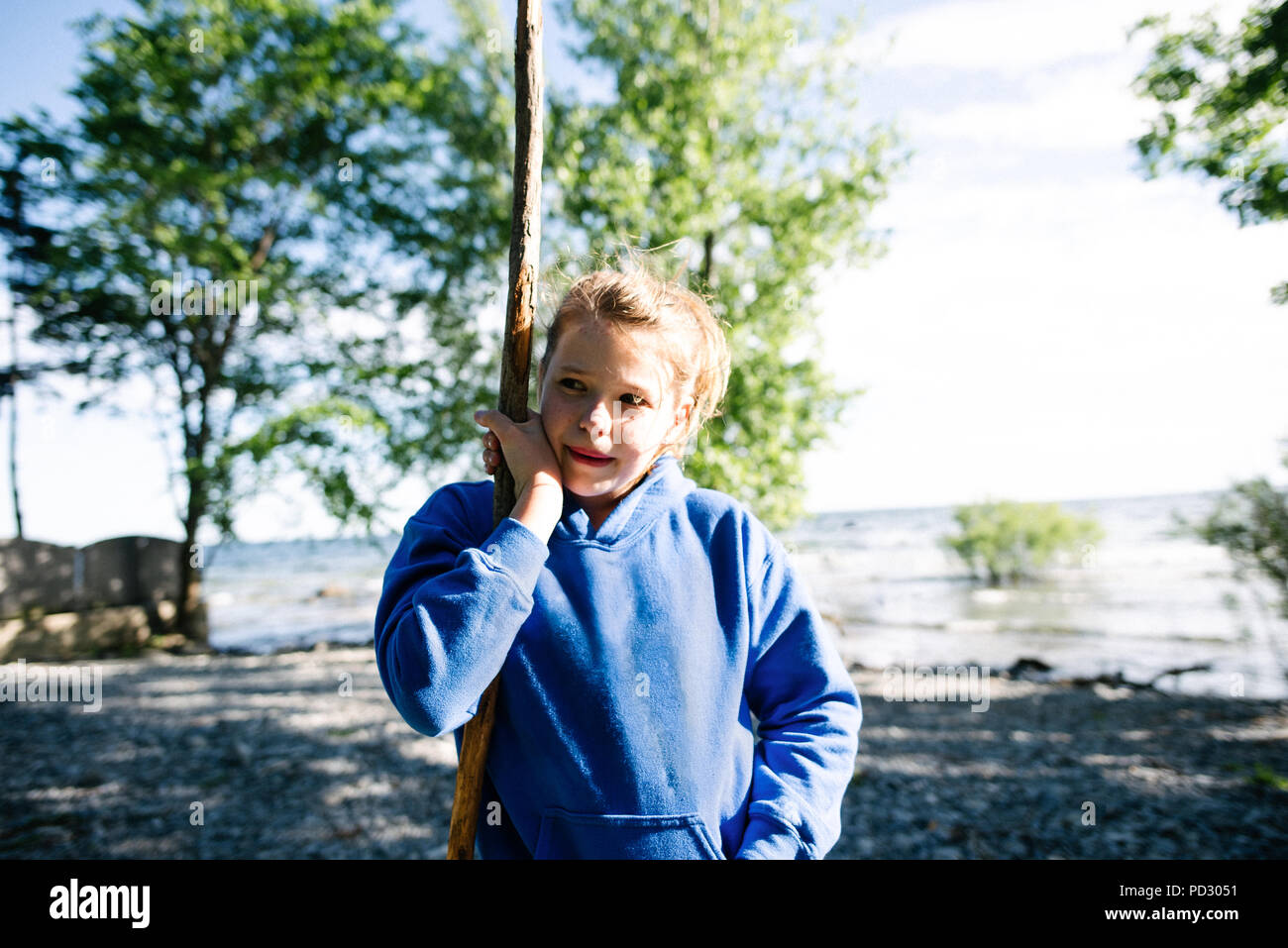 Mädchen erkunden Ufer mit Stick, Kingston, Kanada Stockfoto