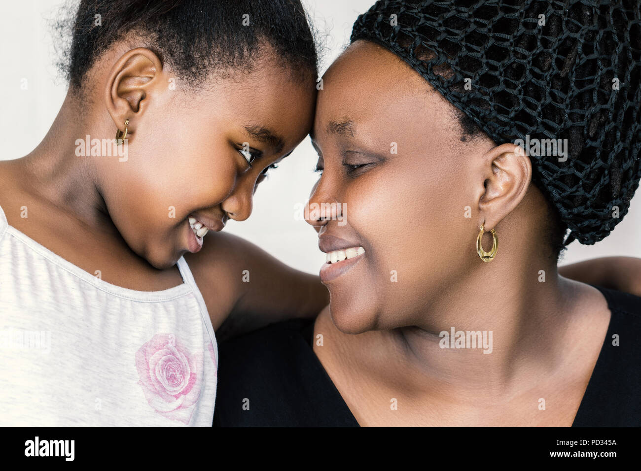 Nahaufnahme Gesicht schoss der afrikanischen Mutter und Tochter an jedem anderen suchen. Ausschreibung Nahaufnahme Portrait von Kid Kopf mit Mutter gegen Weiße isoliert Stockfoto