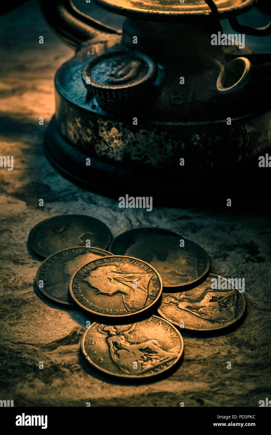 Alte Britische penny Münzen durch eine Öllampe beleuchtet. Stockfoto