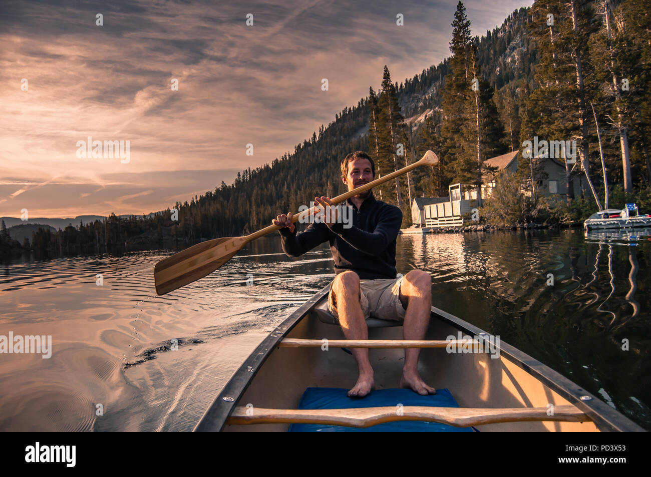 Junger Mann Kanufahren auf Echo Lake, High Sierras, Kalifornien, USA Stockfoto