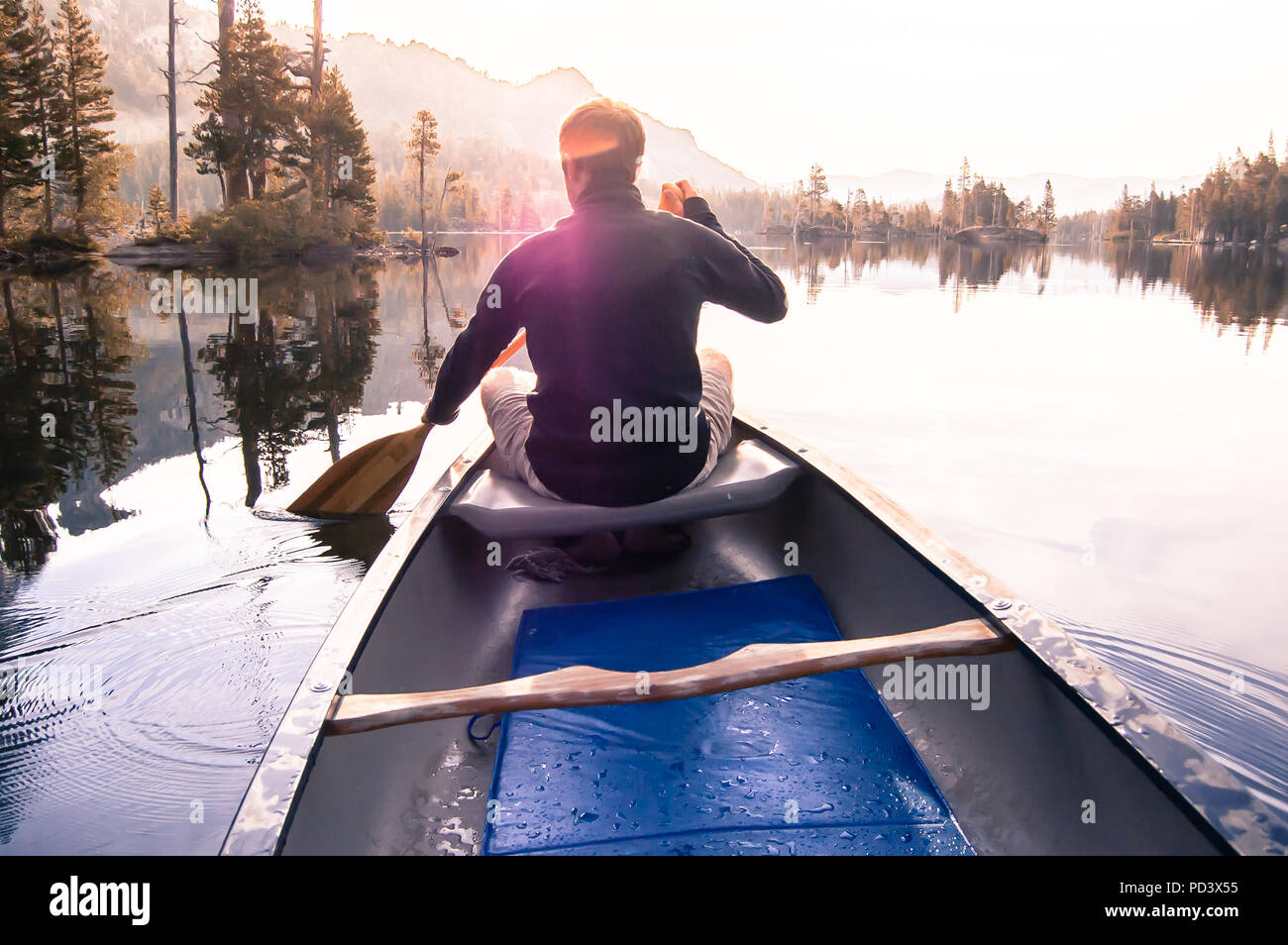 Junger Mann Kanufahren auf Echo Lake, Rückansicht, High Sierras, Kalifornien, USA Stockfoto