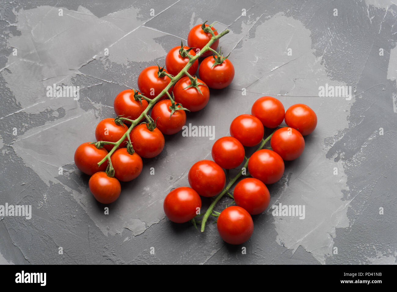 Frische Kirschtomaten auf einem Zweig auf einem schwarzen konkreten Hintergrund. Stockfoto