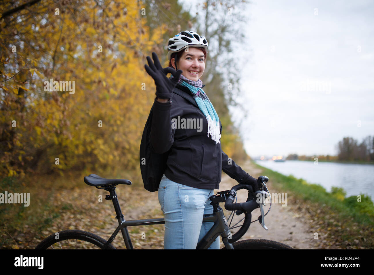Foto von Smiling brunette in Helm und mit Rucksack mit Ok auf dem Fahrrad Stockfoto