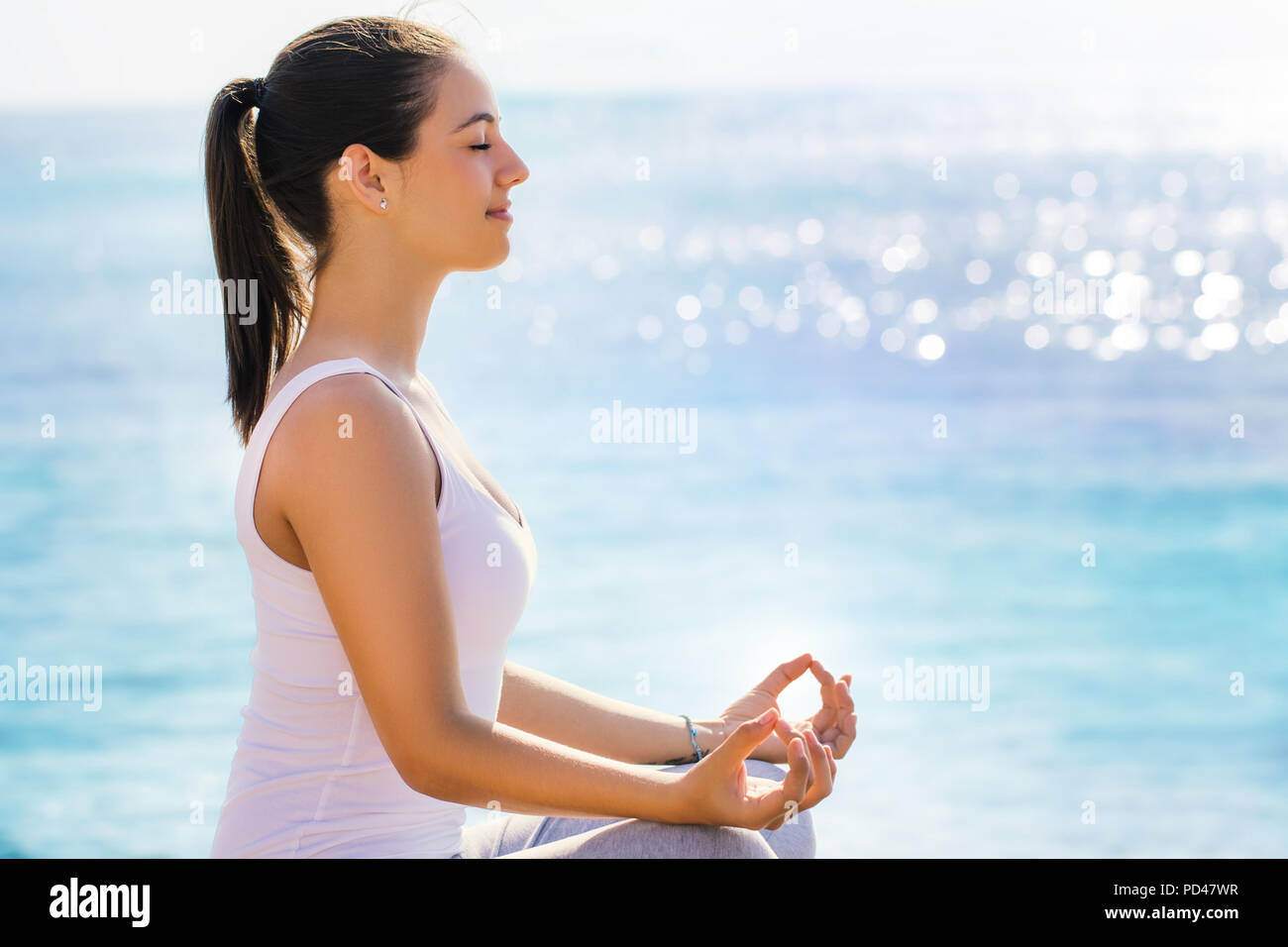 Nahaufnahme Seite Seitenansicht Porträt der jungen Frau in Freizeitkleidung auf der Suche nach spiritueller Erleuchtung neben Meer. Mädchen Yoga Übung in der frühen Mo Stockfoto