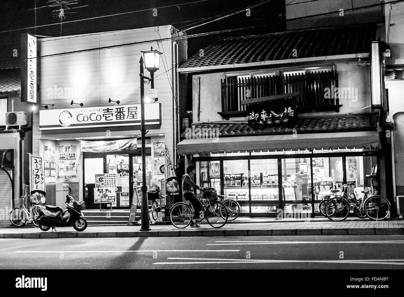 Kyoto, Japan. Ein Mann auf einem Fahrrad in der Nähe des Store auf Gion Straße bei Nacht Stockfoto