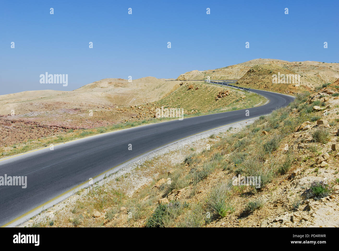 Kurvige asphaltierte Straße führt durch die Wüste, auf einen Berg, blauer Himmel mit Text Raum Stockfoto