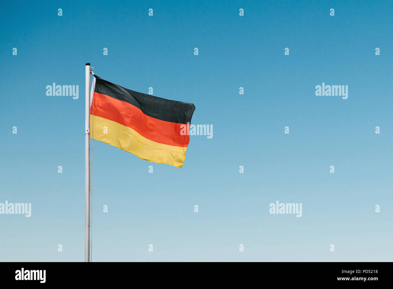 Deutsche Fahne im Wind gegen den blauen Himmel. Stockfoto