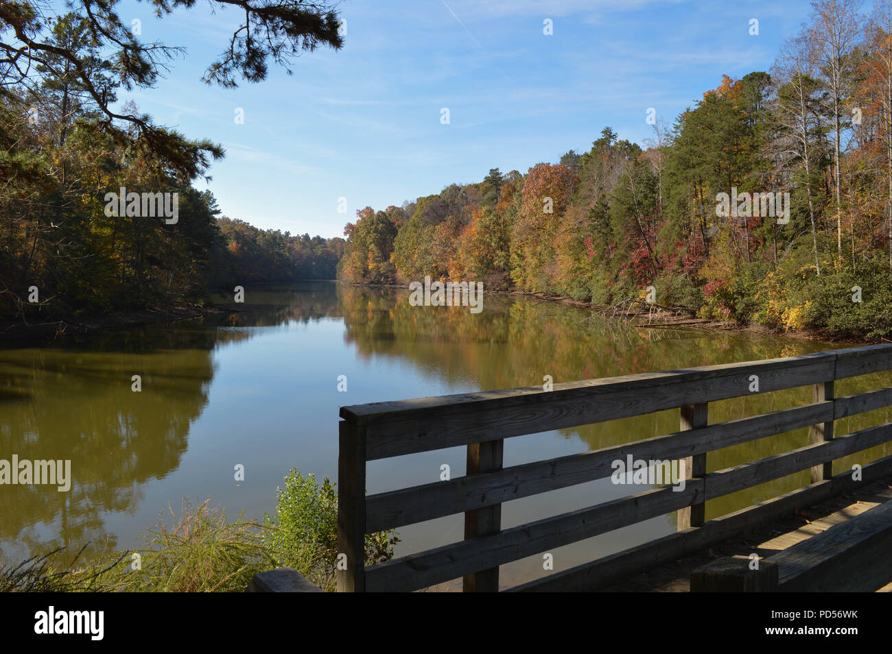 Herbst Schönheit gesehen von einem rustikalen hölzernen Brücke mit Blick auf einen ruhigen See Stockfoto