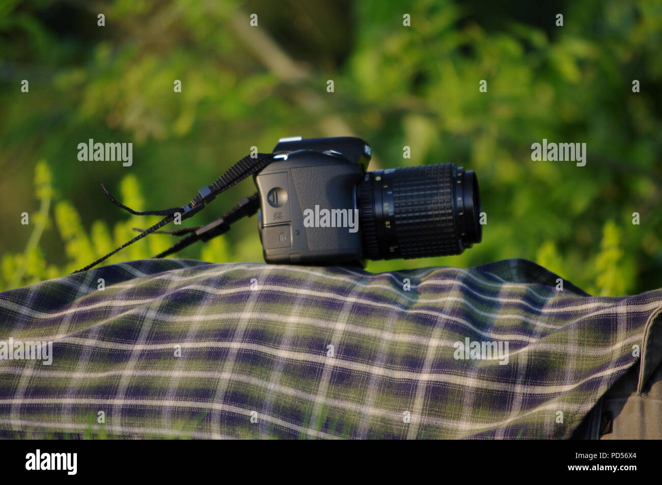 Kamera ruht auf Green Tartan eines Fotografen Shirt, als er auf dem River Exe Bank liegt. Exeter, Devon, Großbritannien. Stockfoto