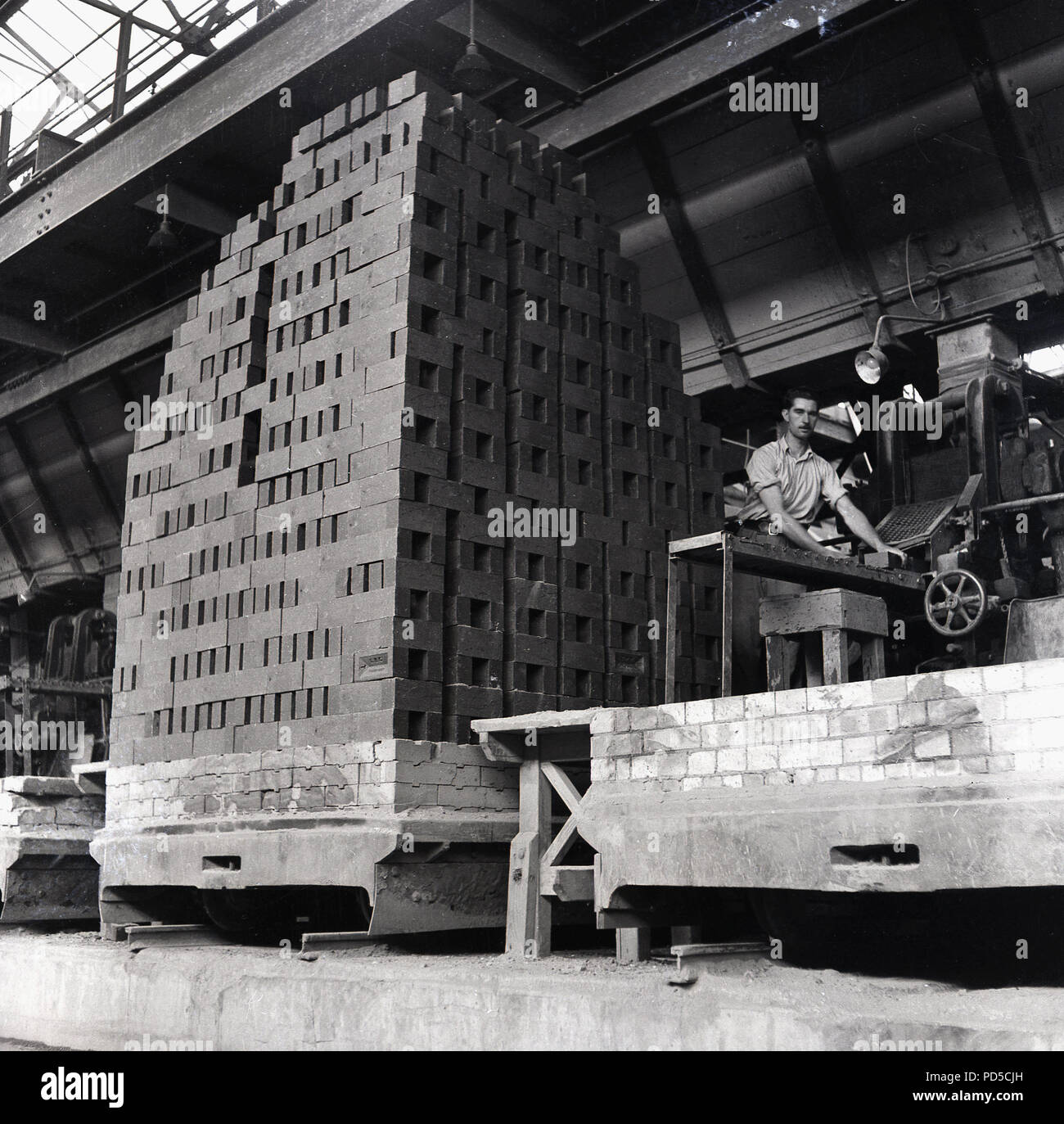 1950 s, London Brick Company, männliche Arbeiter am Band Maschine besidee ein großer grosser kürzlich gebranntem Ton Steine stapeln, Stewartby, Bedford, England, UK. Stockfoto