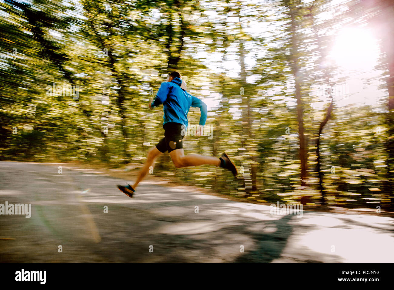 Mann runner schnell im Herbst Wald Straße, verschwommene Bewegung Stockfoto
