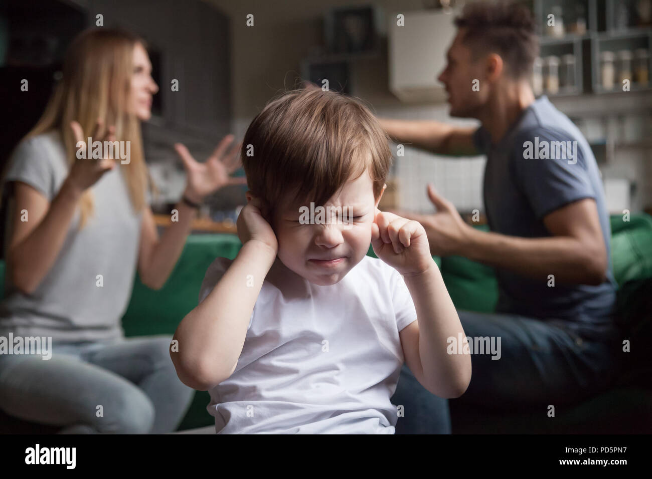 Frustriert kid Sohn legt die Finger in die Ohren, während die Eltern streiten Stockfoto