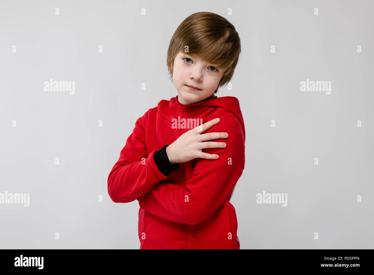 Cute zuversichtlich ernste kaukasischen kleinen Jungen in roten Pullover  mit verschränkten Armen auf grauem Hintergrund Stockfotografie - Alamy