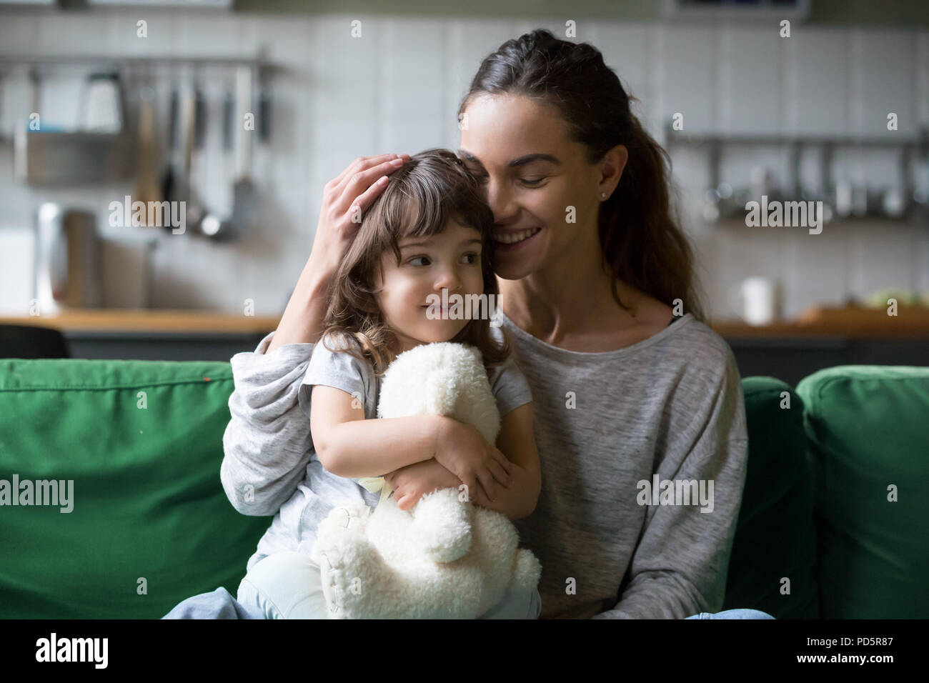 Gerne einzelne Mutter umarmt süße Tochter, die Pflege und suppo Stockfoto