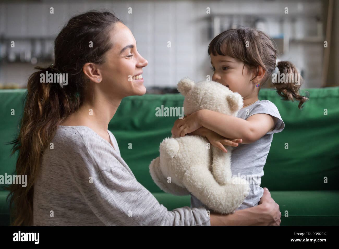 Lächelnde Mutter umarmt niedlichen Tochter Liebe und Pflege Stockfoto