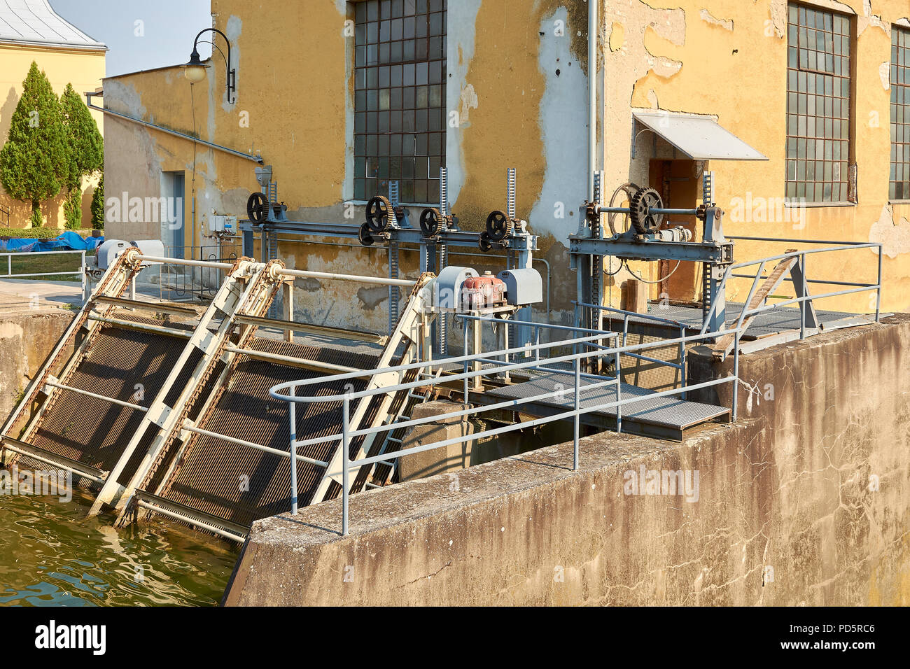 Alte Wasserkraftwerk mit verrosteten Gang, Wassertank und dem gelben Gebäude mit gebrochenen Gips Stockfoto