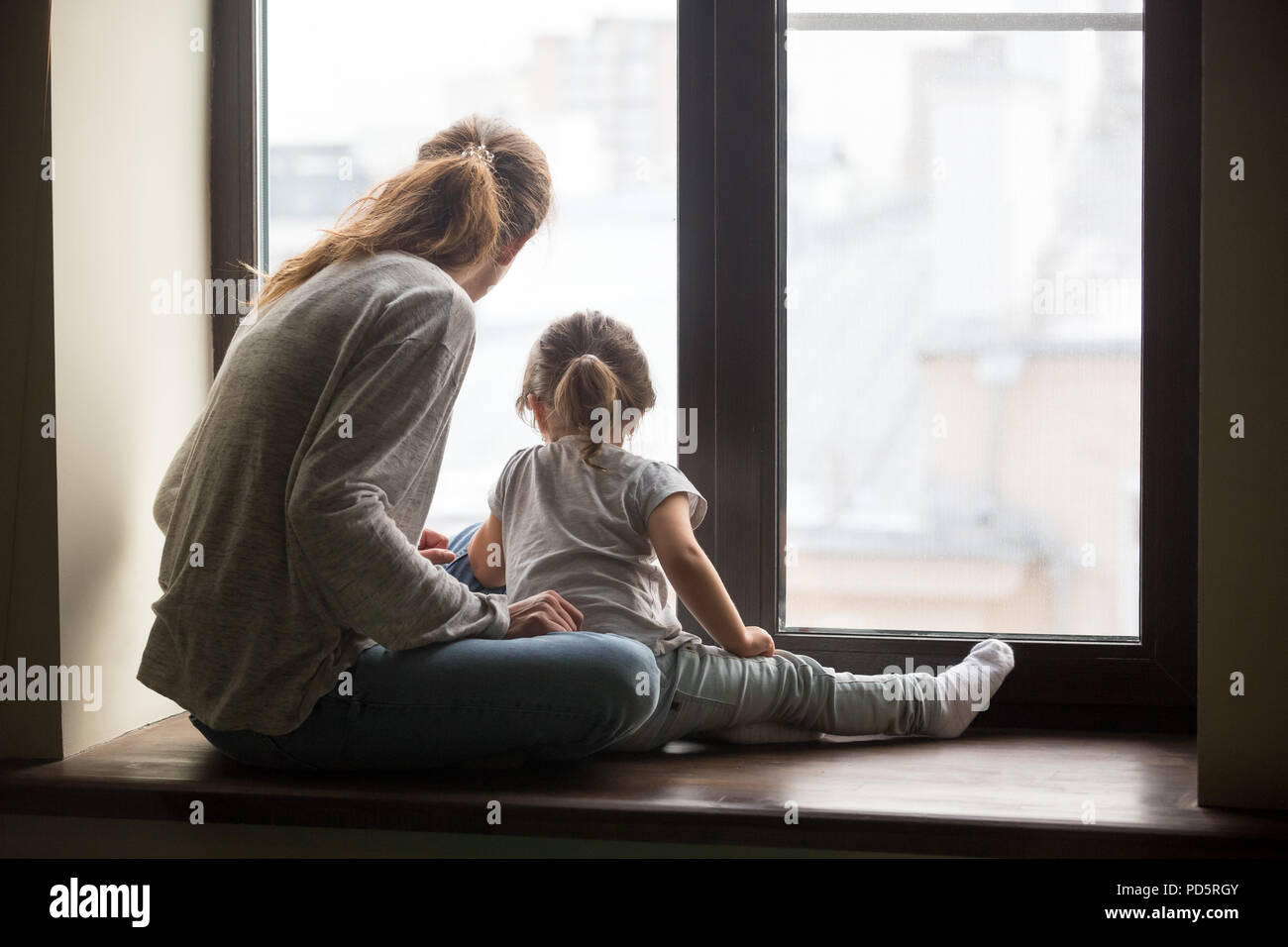 Ansicht von hinten am Kind Tochter und Mutter sitzen auf Einstiegschweller Stockfoto